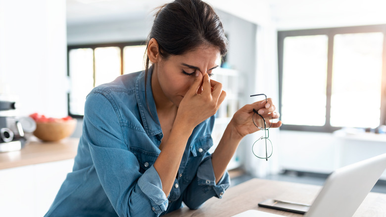 Woman holds fingers nose frustration