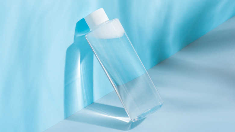 Micellar water resting on a blue wall.