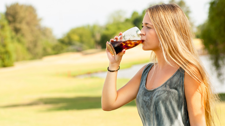 Woman drinking too much soda outside