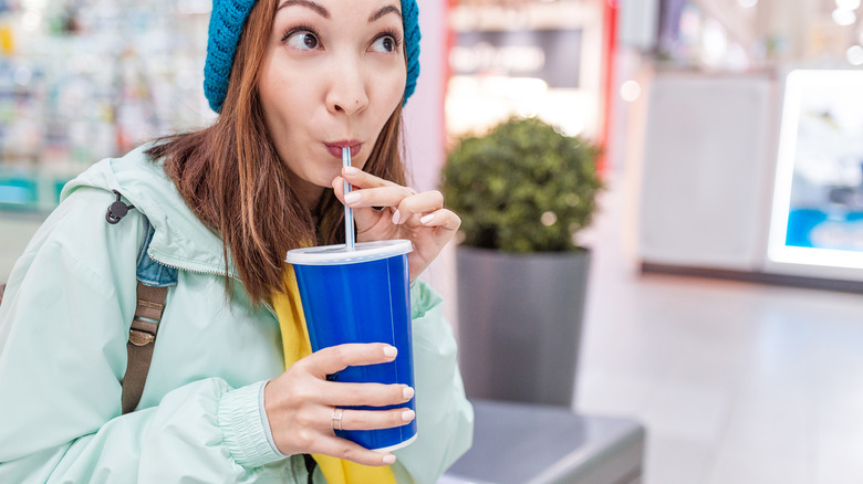 woman drinking too much soda from straw and plastic cup