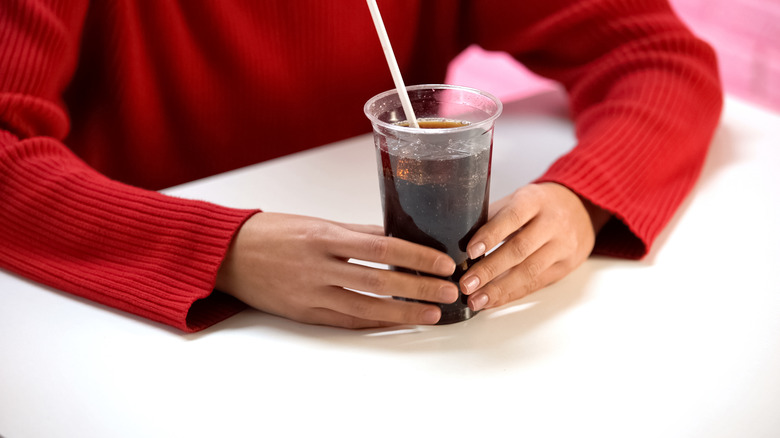 hands holding cup of soda