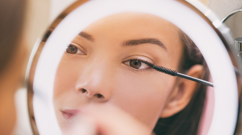 Woman applying mascara to eyelashes