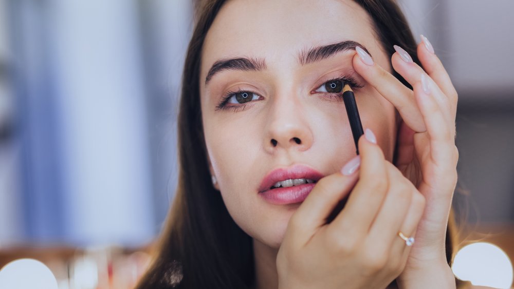 A woman applying thick eyeliner