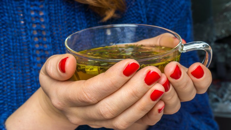 woman cupping a mug of green tea