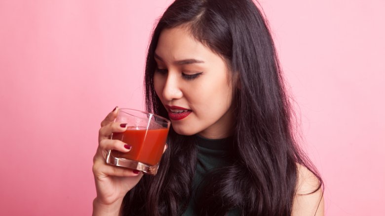 woman holding a glass of tomato juice