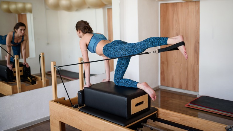 Woman doing Pilates on a reformer with fitness bands