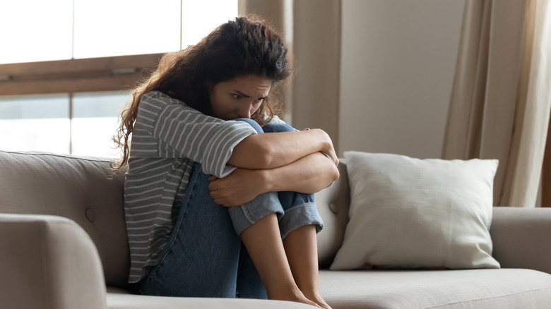 Regretful woman curled up on sofa