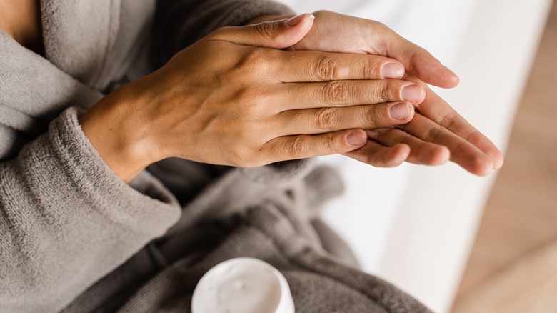 person rubbing balm on their hands