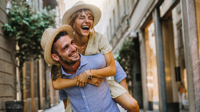 man carrying girlfriend on back smiling