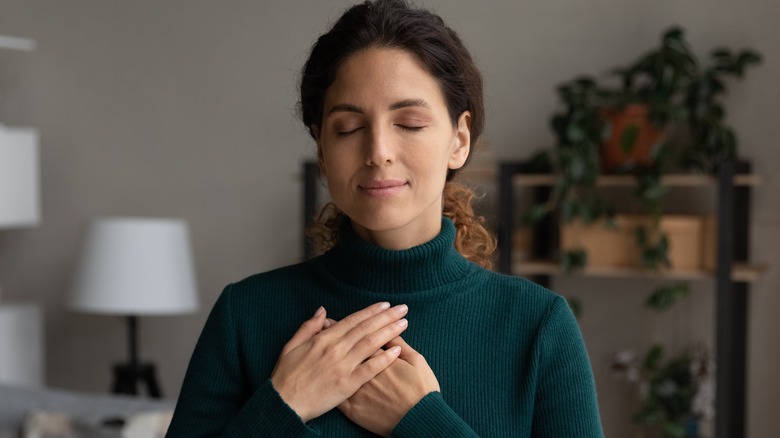 woman closing eyes with hands over heart