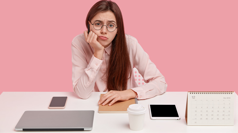 woman at desk looking unhappy