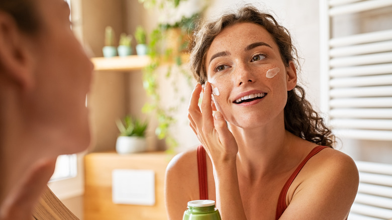 Woman puts cream on face