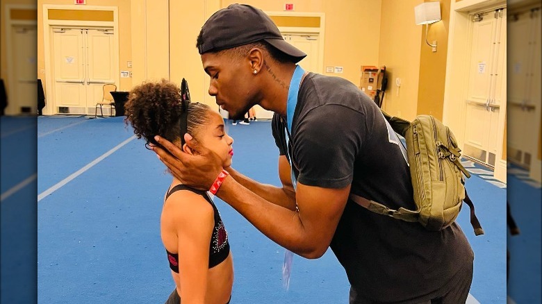 La'Darius Marshall kissing his little sister on the forehead at a cheer competition