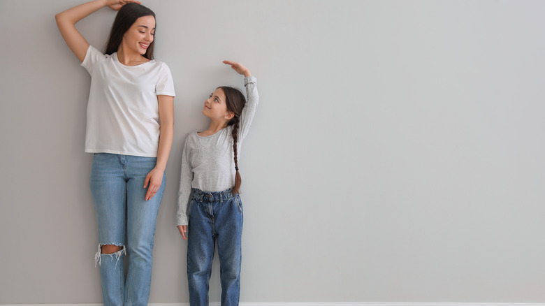 mother and daughter measuring their heights with their hands