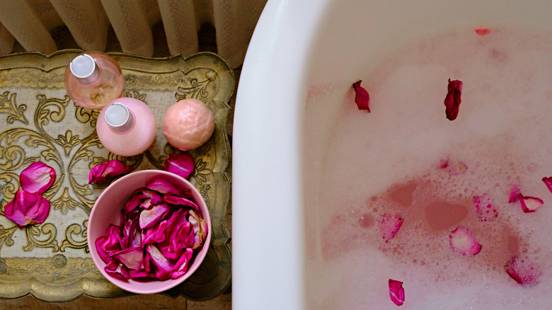 A bath tub with rose petals and a pink bath bomb