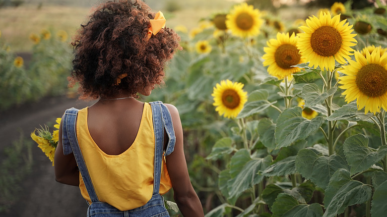 Woman in overalls in sunflower field 