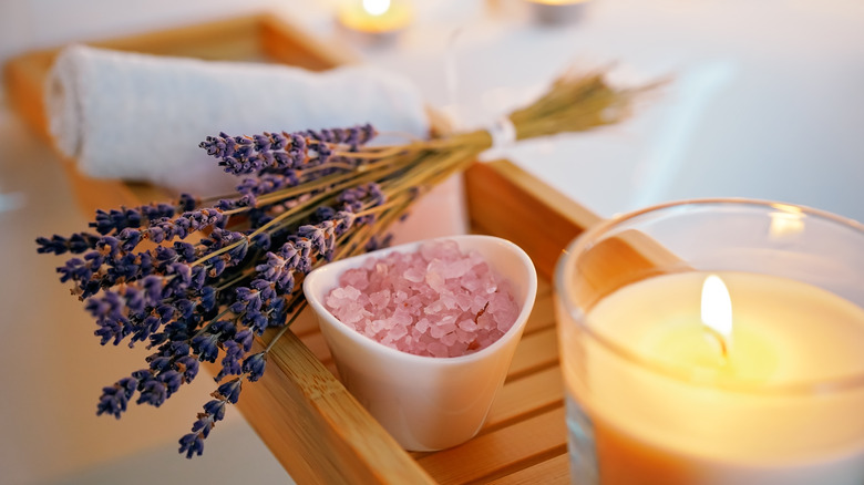 lavender, salt, and a candle over a bathtub 