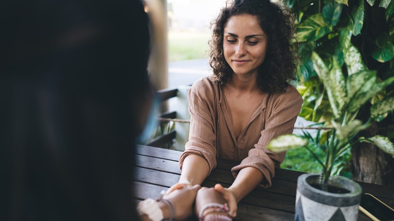 smiling women holding hands sitting