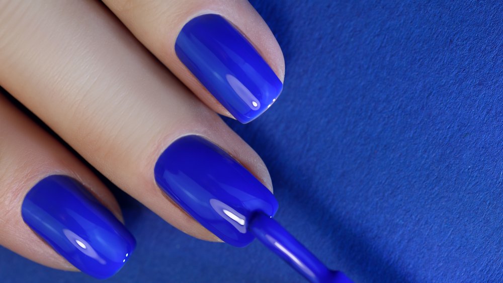 Woman applying blue polish to nails
