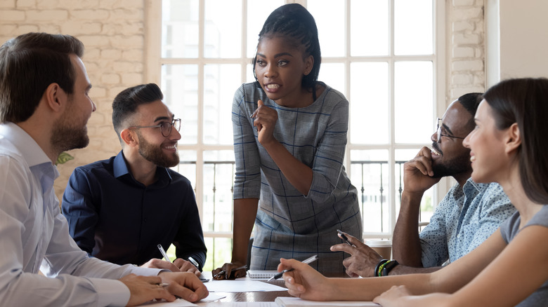 Female boss speaks to her employees at a table