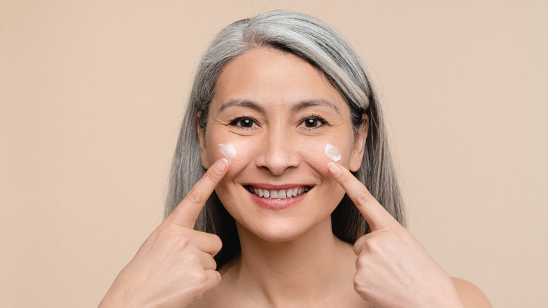 woman applying moisturizer to cheeks