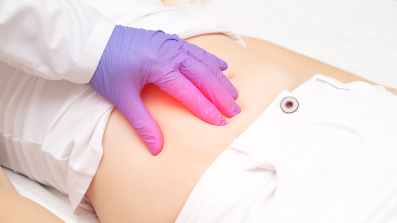 A doctor pressing down on a patient's stomach area