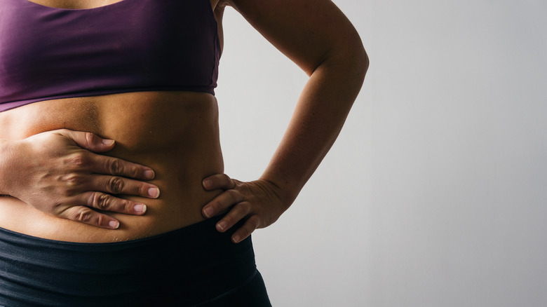 a women holding her stomach over her belly button area