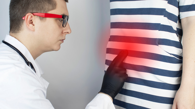 A doctor touching th area near the belly button of a patient