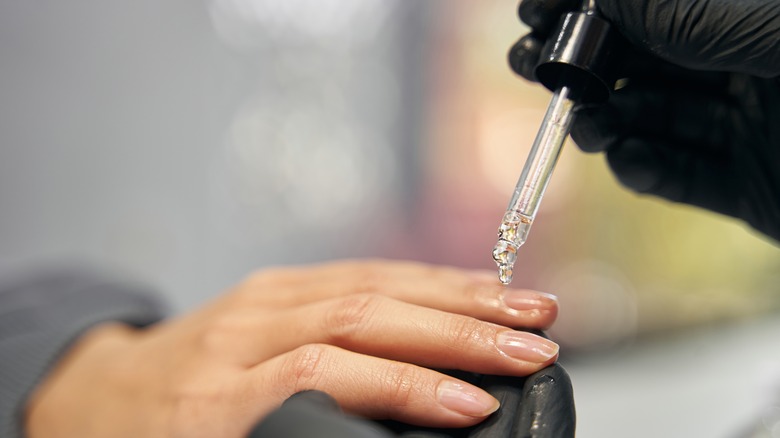 Manicurist putting oil on cuticles