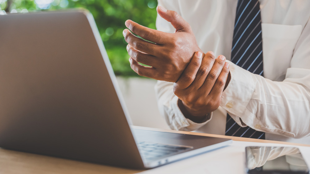 Male business man rubbing his wrist in front of the computer 