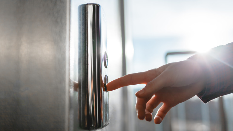 Thumb pressing button on elevator