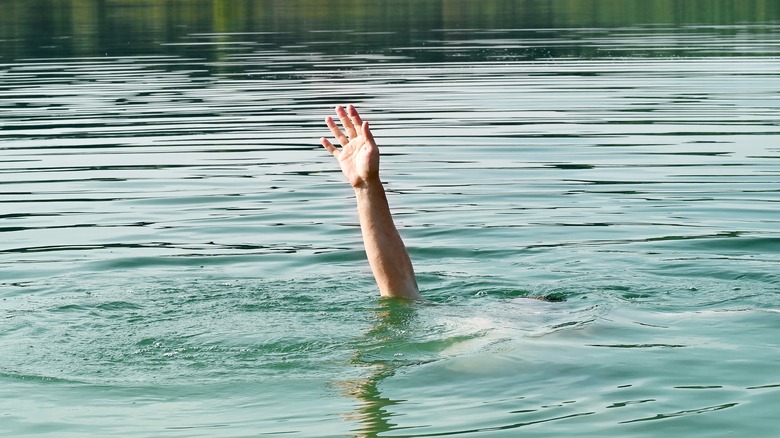 A hand reaches out of the water