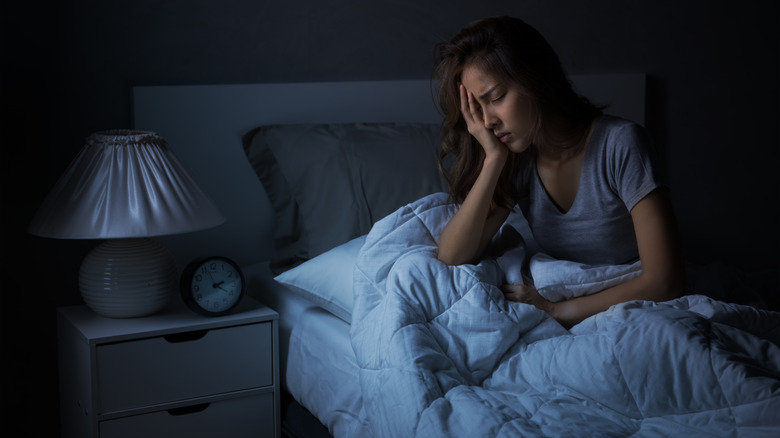 A woman sits up in bed