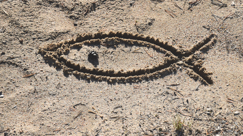 An Ichthys drawn in sand 