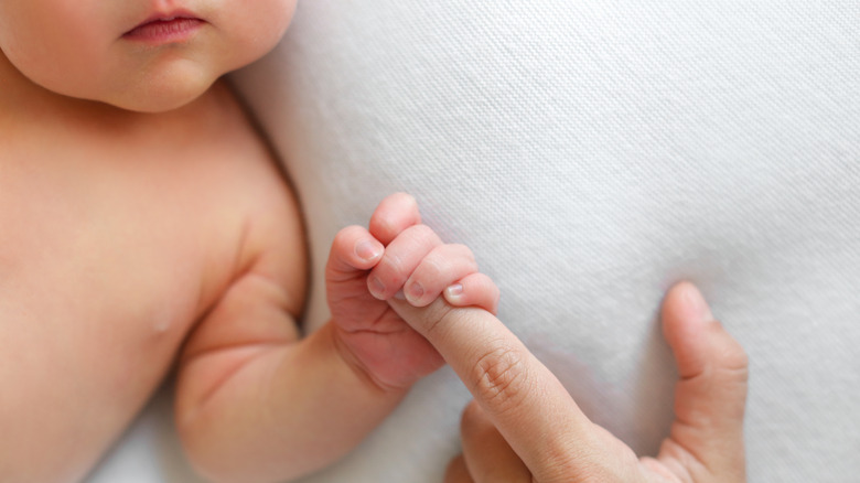 Baby holding mom's finger