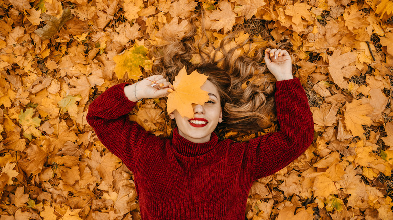 Happy woman laying on leaves