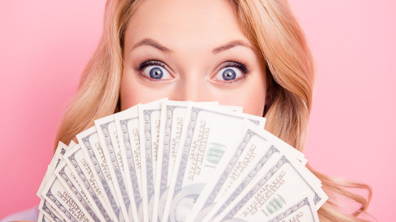 Woman with money covering half of face