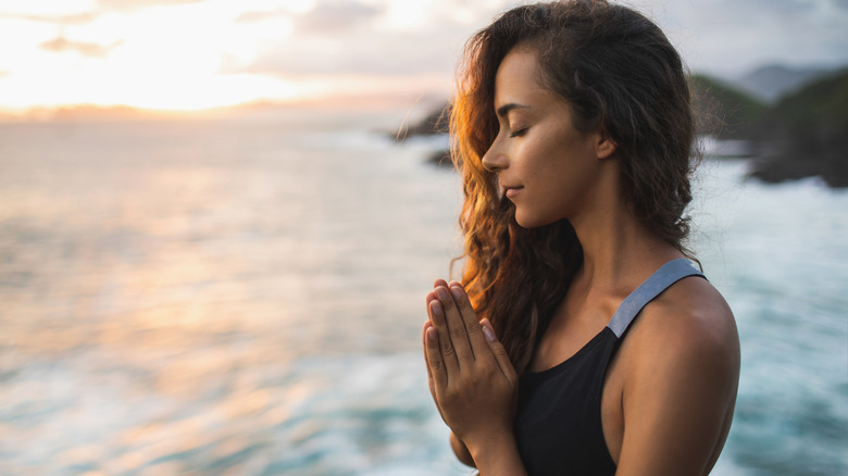 Woman meditating or praying on beach