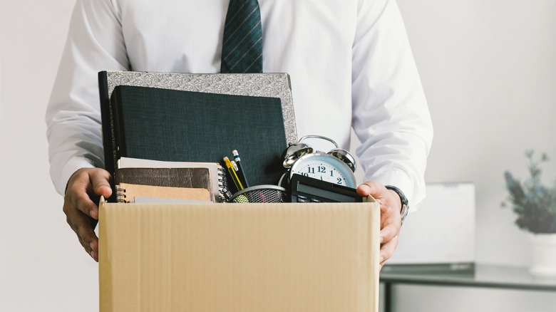 Fired employee holds a box with their things