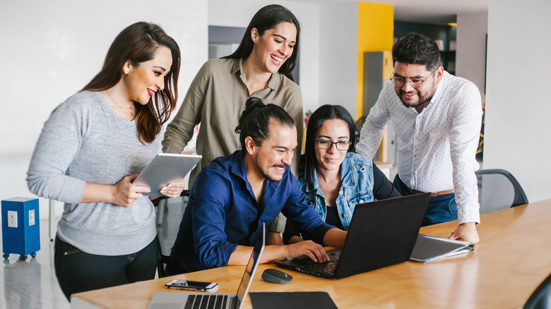 People at work gathering around a laptop