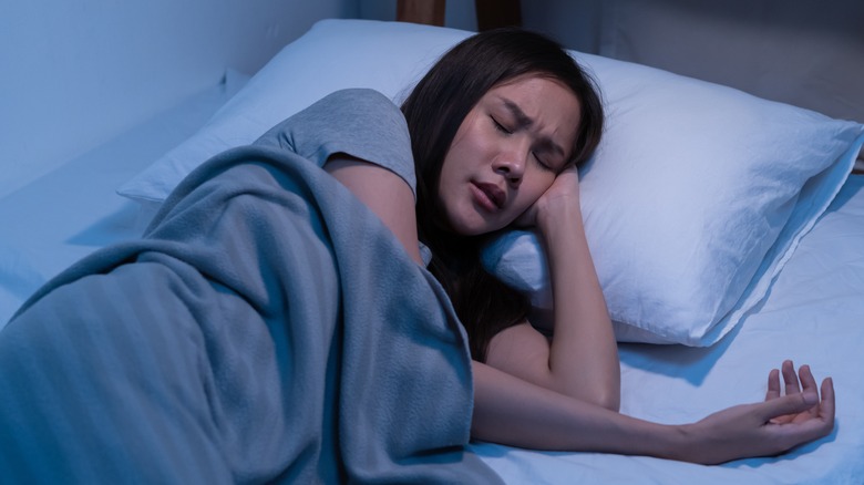 Woman asleep in bed suffering from nightmare