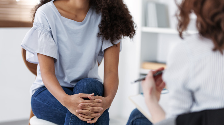 Seated young woman speaking to a therapist