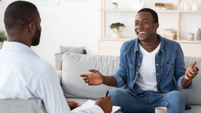 man smiling while talking to male therapist