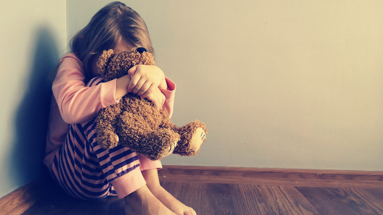 scared child clutching teddy bear