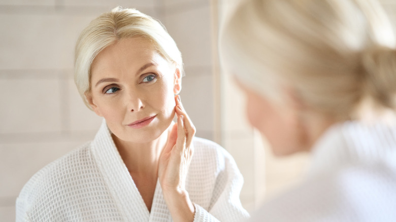 Woman checking her skin in the mirror