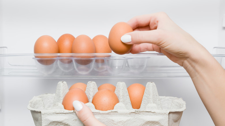 woman selecting eggs from refrigerator