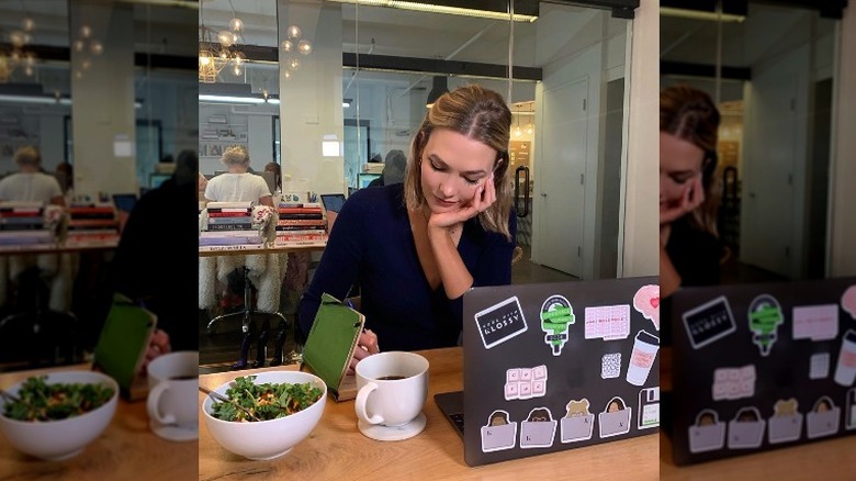 Karlie Kloss with a salad on a computer