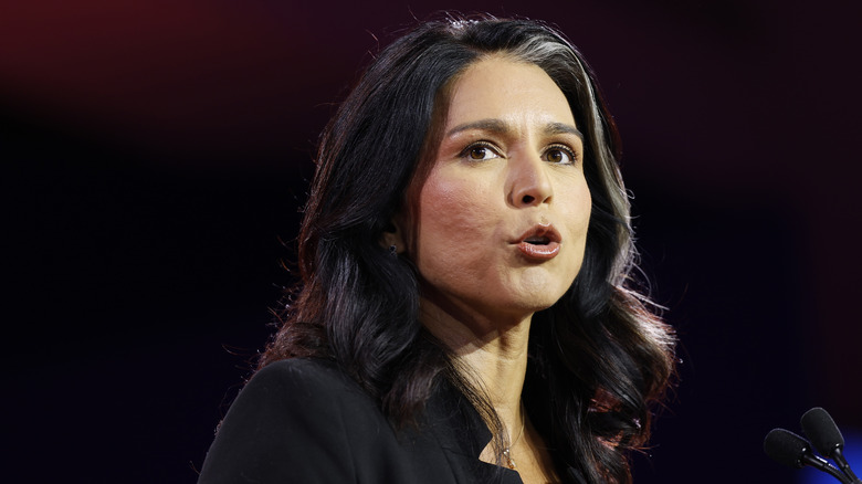 Tulsli Gabbard speaking onstage in a black shirt