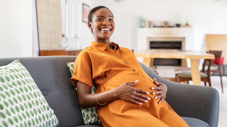 Pregnant woman sitting holding belly