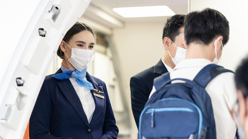 Flight attendant wearing a mask near passengers